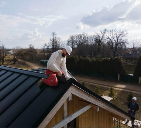 man completes peak of metal roof